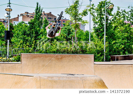 A young man practicing BMX and performing tricks at the skatepark A young man practicing BMX and performing tricks at the skatepark 141372190
