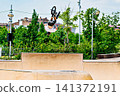 A young man practicing BMX and performing tricks at the skatepark 141372191