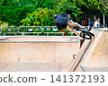 A young man practicing BMX and performing tricks at the skatepark 141372193