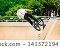 A young man practicing BMX and performing tricks at the skatepark 141372194