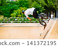 A young man practicing BMX and performing tricks at the skatepark 141372195