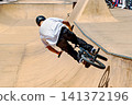 A young man practicing BMX and performing tricks at the skatepark 141372196