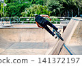 A young man practicing BMX and performing tricks at the skatepark 141372197