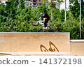 A young man practicing BMX and performing tricks at the skatepark 141372198