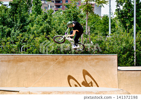 A young man practicing BMX and performing tricks at the skatepark 141372198