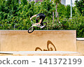 A young man practicing BMX and performing tricks at the skatepark 141372199