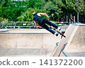 A young man practicing BMX and performing tricks at the skatepark 141372200