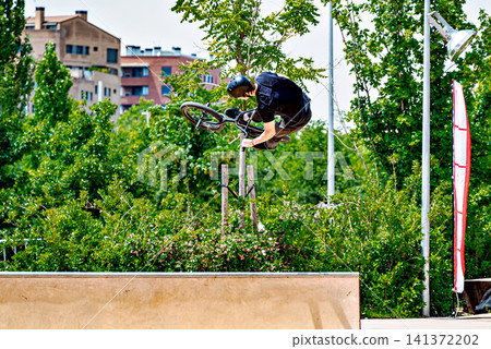 A young man practicing BMX and performing tricks at the skatepark 141372202