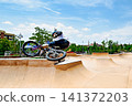A young man practicing BMX and performing tricks at the skatepark 141372203