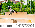 A young man practicing BMX and performing tricks at the skatepark 141372204