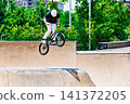A young man practicing BMX and performing tricks at the skatepark 141372205