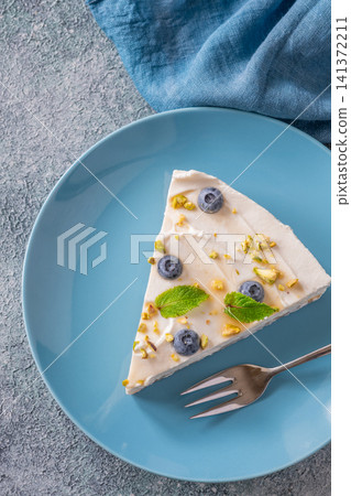 Creamy Mascarpone Cheesecake Slice Served With Blueberries Pistachios Maple Syrup And Mint Leaves Creamy Mascarpone Cheesecake Slice Served With Blueberries Pistachios Maple Syrup And Mint Leaves 141372211