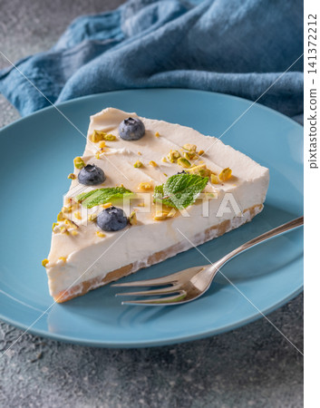 Creamy Mascarpone Cheesecake Slice Served With Blueberries Pistachios Maple Syrup And Mint Leaves 141372212
