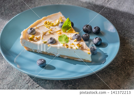 Creamy Mascarpone Cheesecake Slice Served With Blueberries Pistachios Maple Syrup And Mint Leaves 141372213
