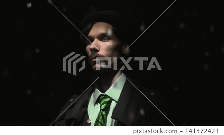 Serious man in dark hat with falling snow against black background Serious man in dark hat with falling snow against black background 141372421