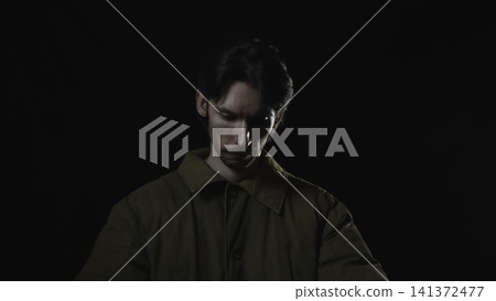 Solitary young man in dramatic low key lighting 141372477
