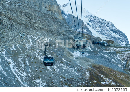 The Eiger Express cable car winds its way up a rugged, rocky cliff face in Grindelwald, Bern, Switzerland. The Eiger Express cable car winds its way up a rugged, rocky cliff face in Grindelwald, Bern, Switzerland. 141372565