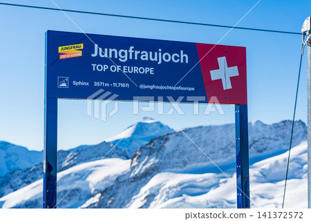 The Sphinx Observatory, with its Jungfraujoch sign and stunning views of the snow-capped mountains. Jungfraujoch, Bern Canton, Switzerland. The Sphinx Observatory, with its Jungfraujoch sign and stunning views of the snow-capped mountains. Jungfraujoch, Bern Canton, Switzerland. 141372572
