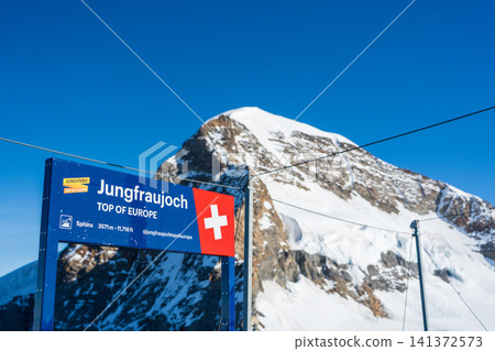 A sign for Jungfraujoch and tourists at the observation deck. Lauterbrunnen, Bern Canton, Switzerland. A sign for Jungfraujoch and tourists at the observation deck. Lauterbrunnen, Bern Canton, Switzerland. 141372573