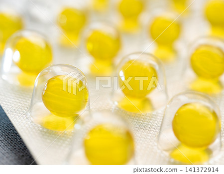 Yellow round medicine pills in blister closeup 141372914
