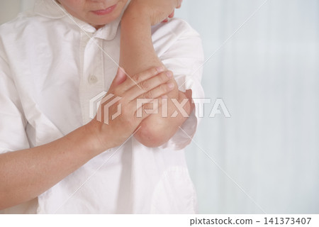 A middle-aged woman suffering from elbow pain touches the affected area. A middle-aged woman suffering from elbow pain touches the affected area. 141373407