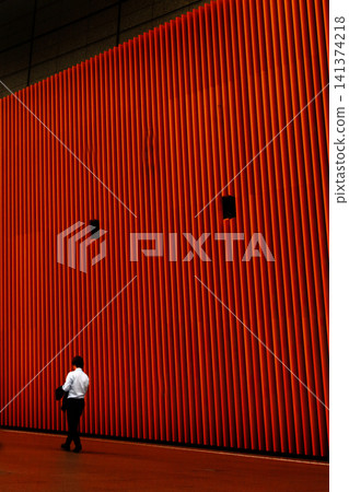 A businessman walking past a red wall A businessman walking past a red wall 141374218