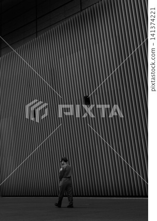 A businessman walking in front of a building window. A businessman walking in front of a building window. 141374221