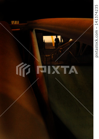 Walking along the passageway visible through the gaps between buildings 141374235