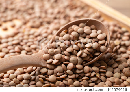 Close-up of raw green lentils in a wooden spoon, high protein plant-based food and meat alternative Close-up of raw green lentils in a wooden spoon, high protein plant-based food and meat alternative 141374616