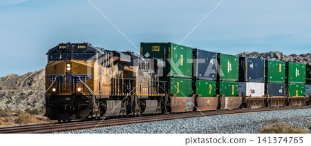 一列聯合太平洋鐵路公司的貨櫃貨運列車氣勢磅礡地穿越美國荒野。 一列聯合太平洋鐵路公司的貨櫃貨運列車氣勢磅礡地穿越美國荒野。 141374765
