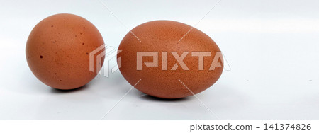 A close-up photo of two brown chicken eggs against a white background. 141374826