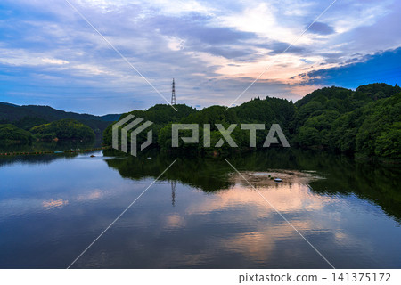 Sunset over Nunome Dam, a water source in Nara City: The golden sky over the mountains and its reflection on the lake surface ① Sunset over Nunome Dam, a water source in Nara City: The golden sky over the mountains and its reflection on the lake surface ① 141375172
