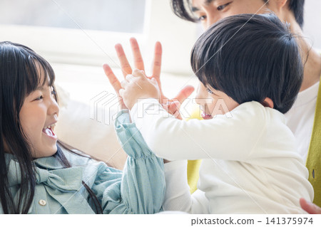孩子們在客廳玩耍,臉上洋溢著笑容,和爸爸擊掌。 孩子們在客廳玩耍,臉上洋溢著笑容,和爸爸擊掌。 141375974
