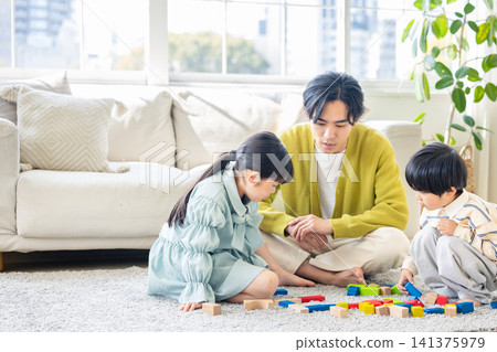 一位父親正在客廳和孩子們玩積木。 141375979