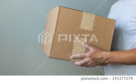 Person Holding Cardboard Shipping Box. Person Holding Cardboard Shipping Box. 141377279