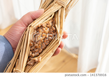 A man holding natto (fermented soybeans) wrapped in rice straw. A man holding natto (fermented soybeans) wrapped in rice straw. 141378916