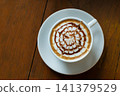 Top view of cappuccino intricate latte art served white cup wooden table creating warm cafe atmosphere for coffee lovers relaxation 141379529