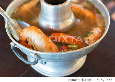 Traditional Thai shrimp tom yum hot pot served fresh herbs aromatic broth offering rich seafood flavors classic spicy meal Traditional Thai shrimp tom yum hot pot served fresh herbs aromatic broth offering rich seafood flavors classic spicy meal 141379537