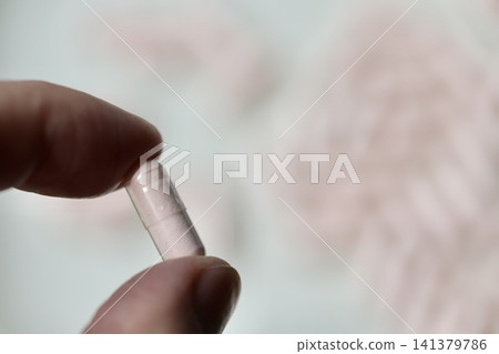 一隻手拿著一個透明膠囊，裡面裝著卡姆果粉；一種維生素補充劑。 141379786