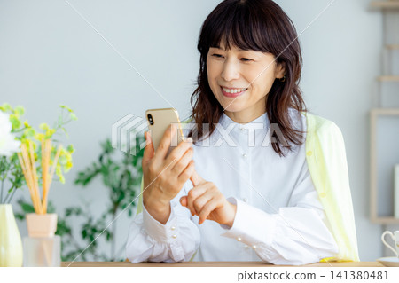 Middle-aged and senior women looking at their smartphones Middle-aged and senior women looking at their smartphones 141380481