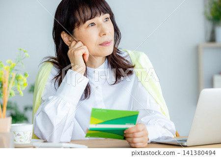一位中年婦女在客廳查看她的儲蓄存摺。 141380494