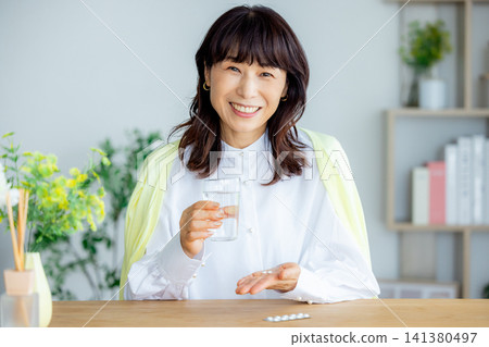 微笑的中年婦女在客廳喝藥 141380497