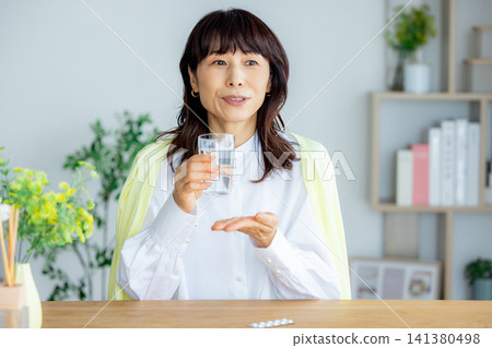 微笑的中年婦女在客廳喝藥 141380498