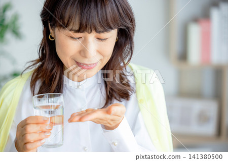 微笑的中年婦女在客廳喝藥 141380500