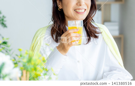 A woman drinking juice with a smile A woman drinking juice with a smile 141380516