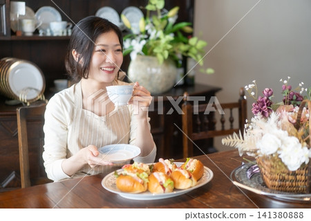 A woman enjoying coffee time at a guesthouse with a traditional Japanese house cafe atmosphere. A woman enjoying coffee time at a guesthouse with a traditional Japanese house cafe atmosphere. 141380888