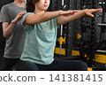 A young Asian woman being instructed by a young male trainer at a personal gym. 141381415