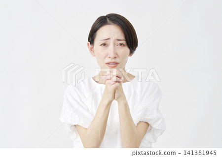 A middle-aged woman pleading against a white background. A middle-aged woman pleading against a white background. 141381945