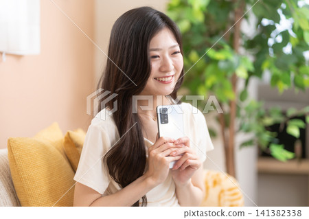 A young woman excitedly anticipating something while holding her smartphone. 141382338