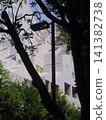 A modern building with an innovative design, towering beyond the silhouettes of trees. 141382738